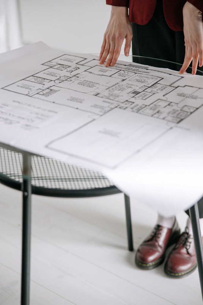 pexels-photo-8962797 Person examining a detailed architectural floor plan on a table indoors with a focus on design.